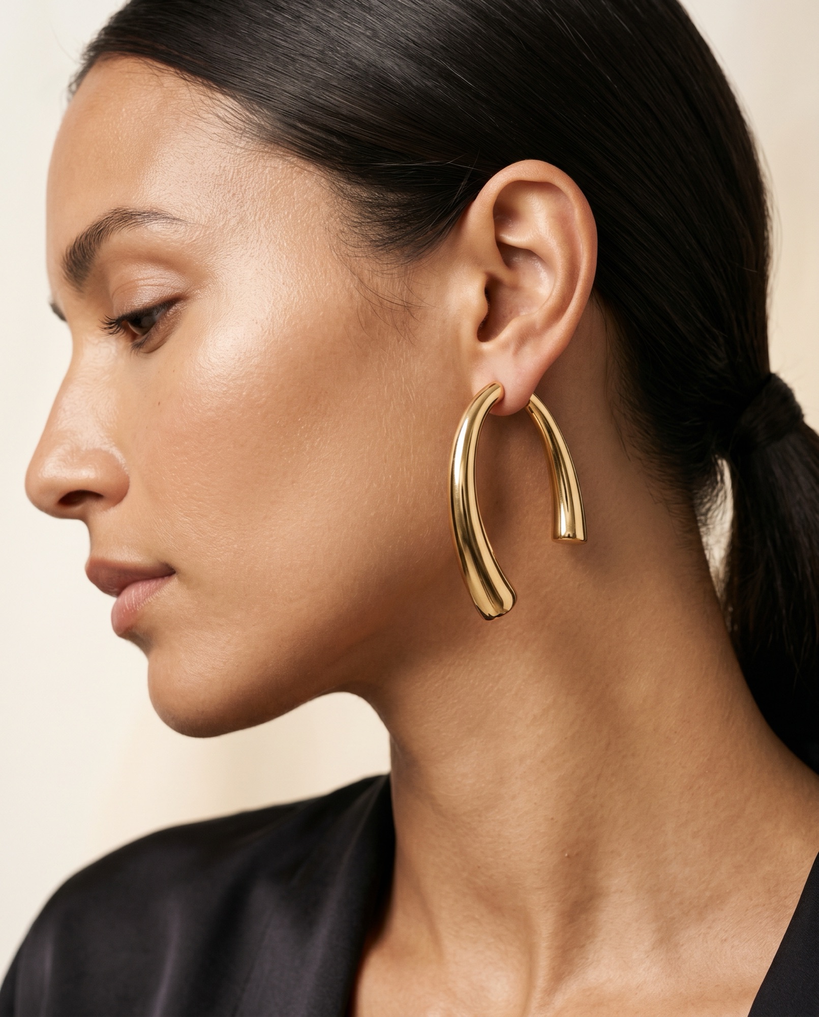 Gros plan éditorial d'une boucle d'oreille arc en or sculptural ARCY